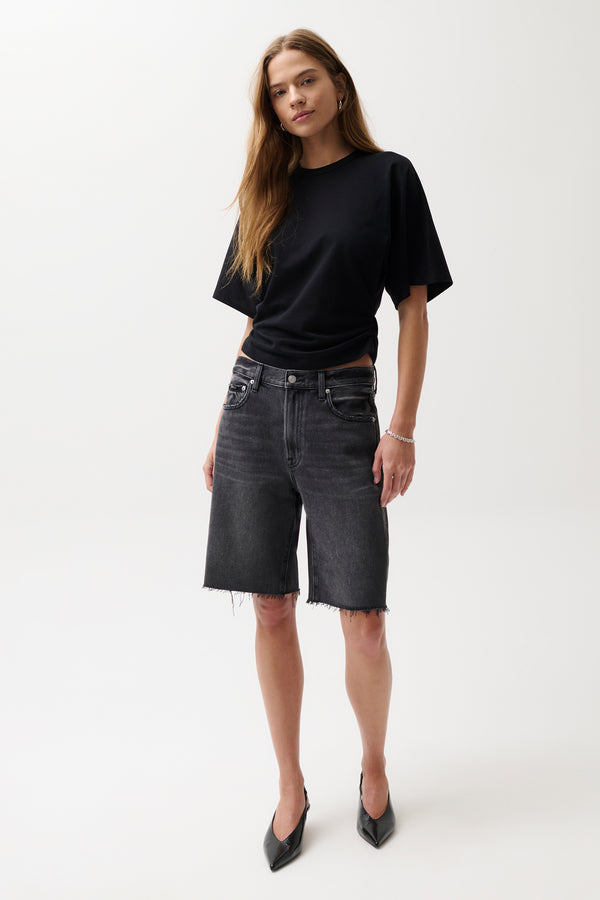 Woman wearing a black t-shirt and gray shorts on a white background