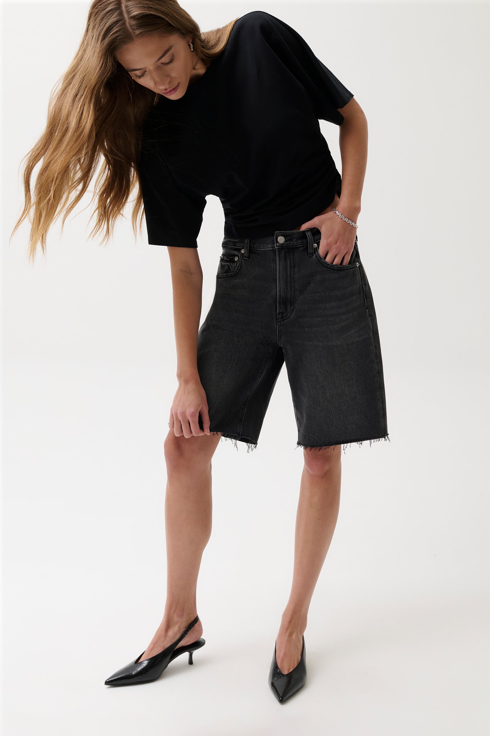 Woman wearing a black t-shirt and black denim shorts on a white background