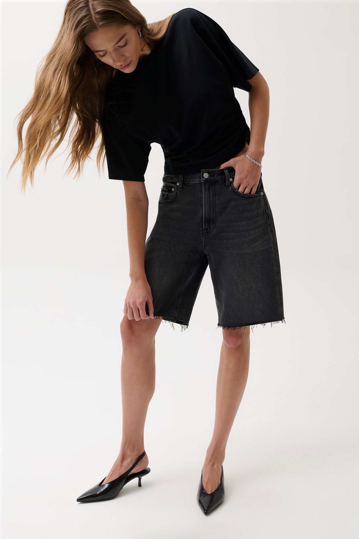 Woman wearing a black t-shirt and black denim shorts on a white background
