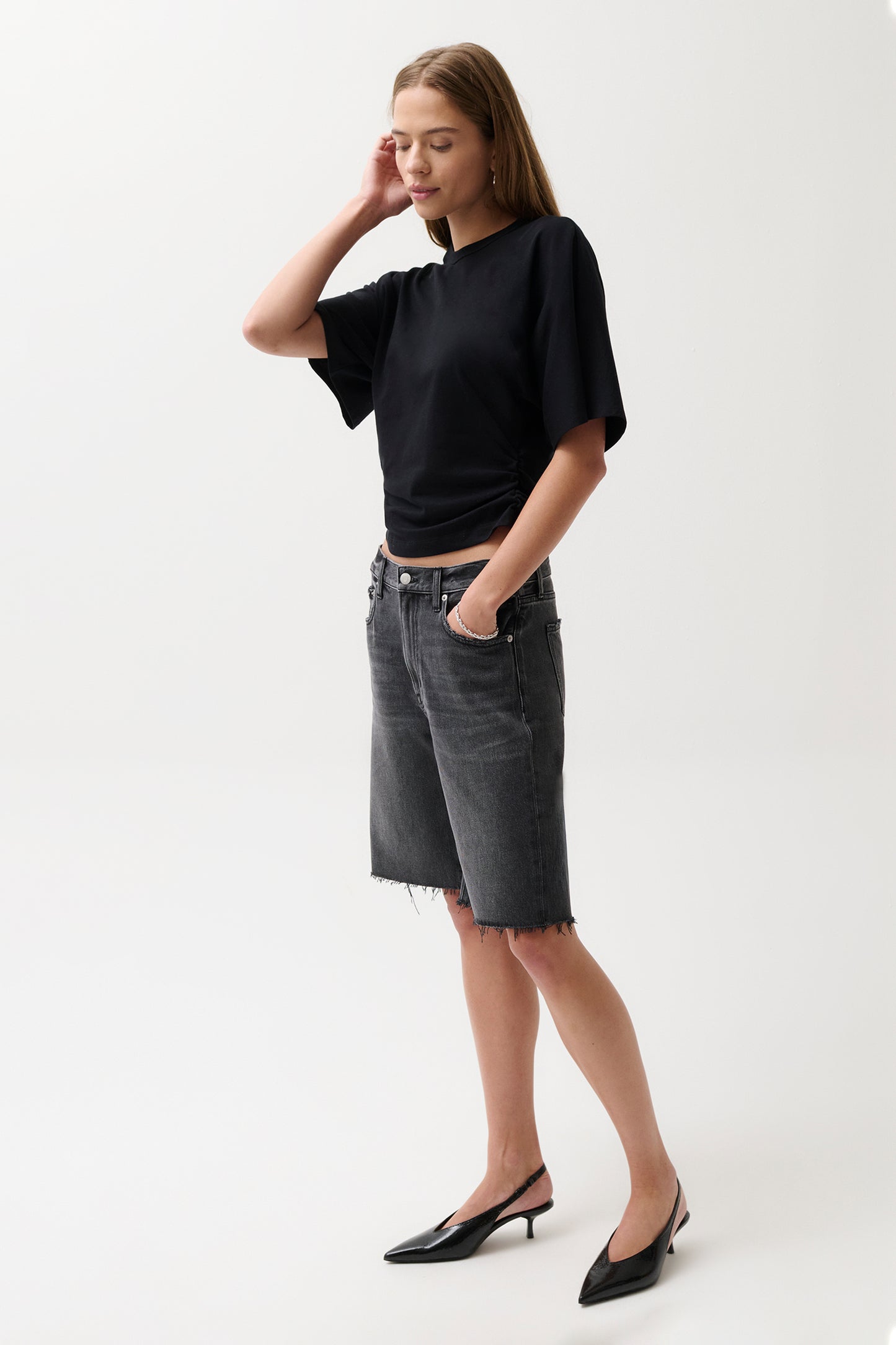 Woman wearing a black top and gray shorts on a white background