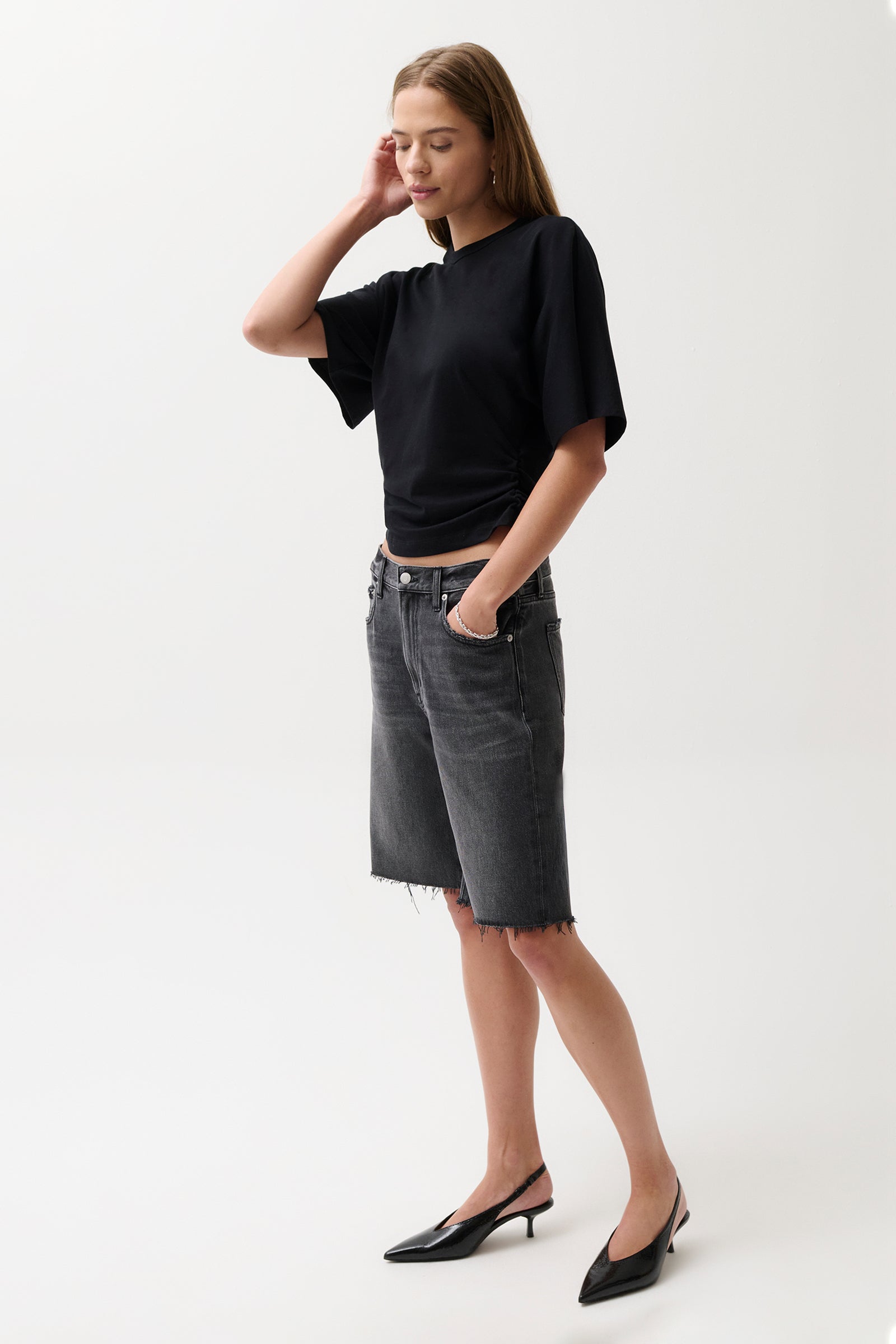 Woman wearing a black top and gray shorts on a white background